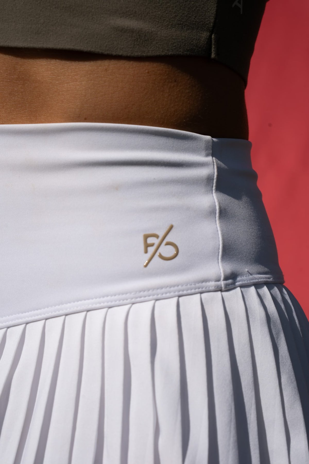 Close-up of the White Onyx Aura Court Skirt waistband with the P/O icon and pleated skirt detail #Color_White Onyx